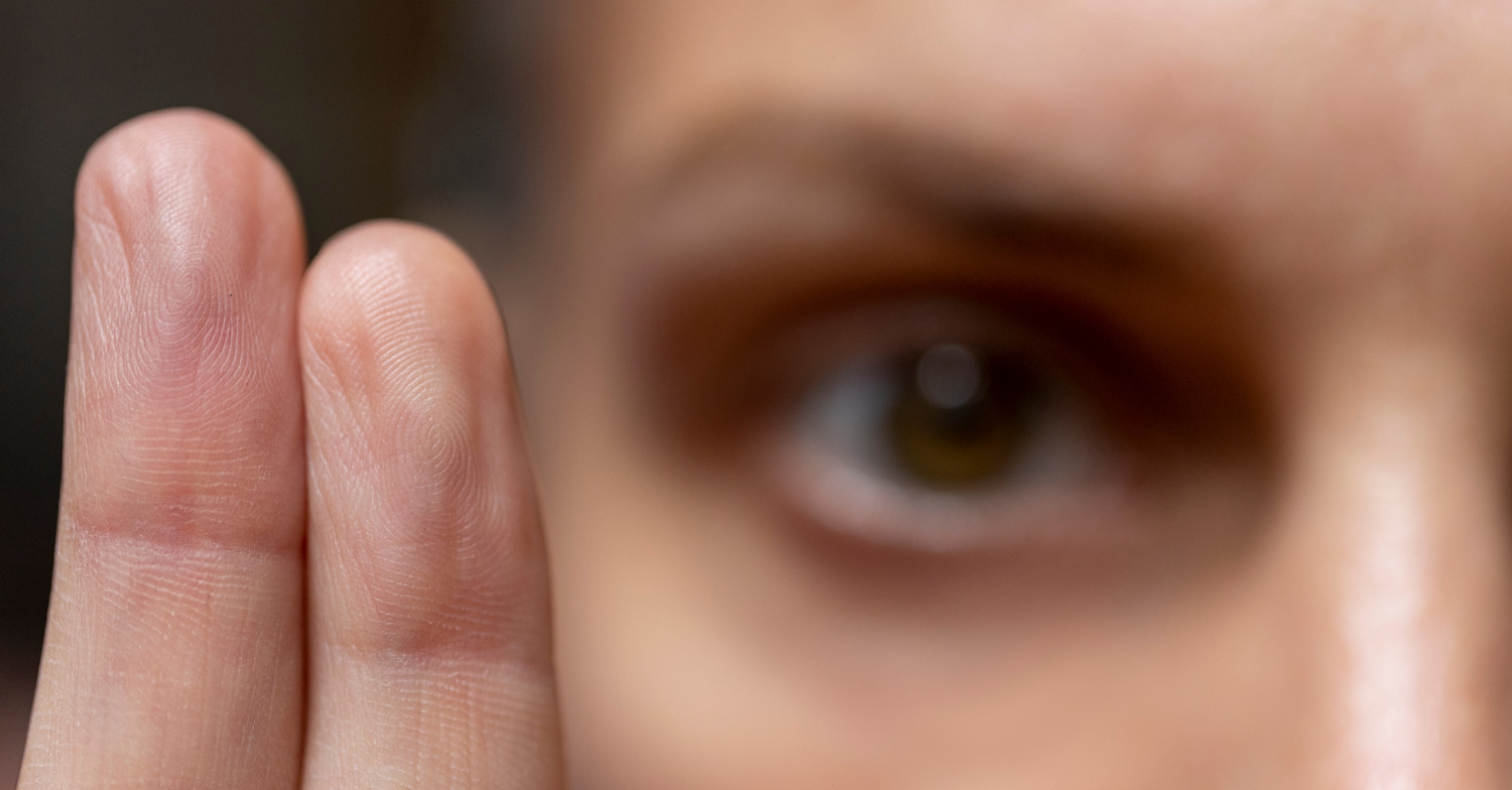 Close-up photo of an eye with two fingers in the foreground used for bilateral stimulation (BLS) in EMDR therapy.